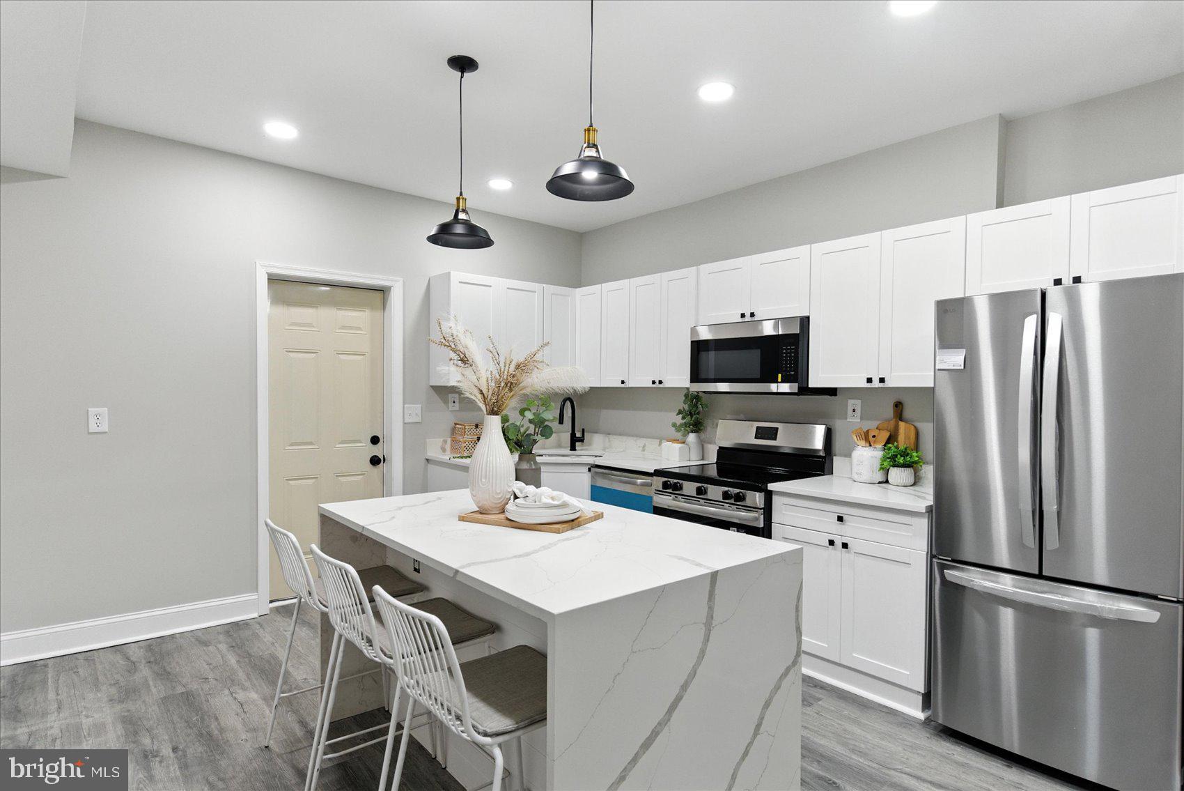 1607 Montpelier Street Baltimore, MD 21218 - Photo 9 of 37 a kitchen with a refrigerator a microwave oven a stove and a center island