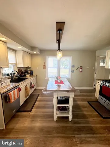a kitchen with kitchen island a stove a counter space and a sink