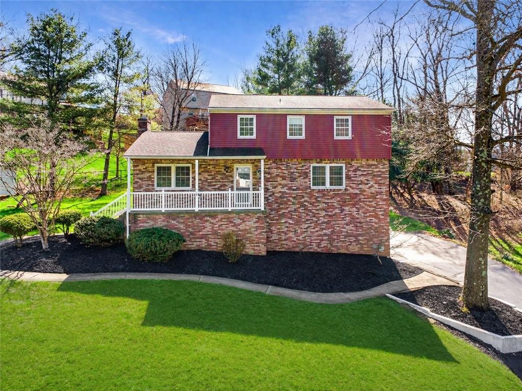 a view of a brick house with a yard potted plants and a large tree