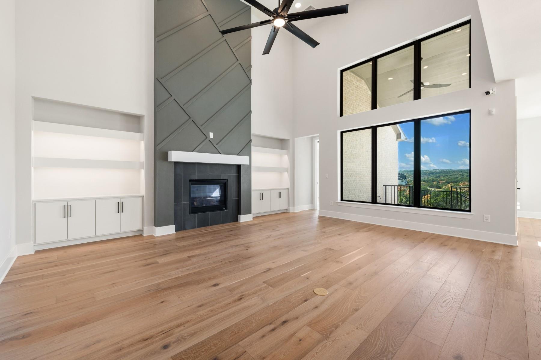 6216 Bower Well Road Austin, TX 78738 - Photo 6 of 31 a view of an empty room with wooden floor fireplace and a window