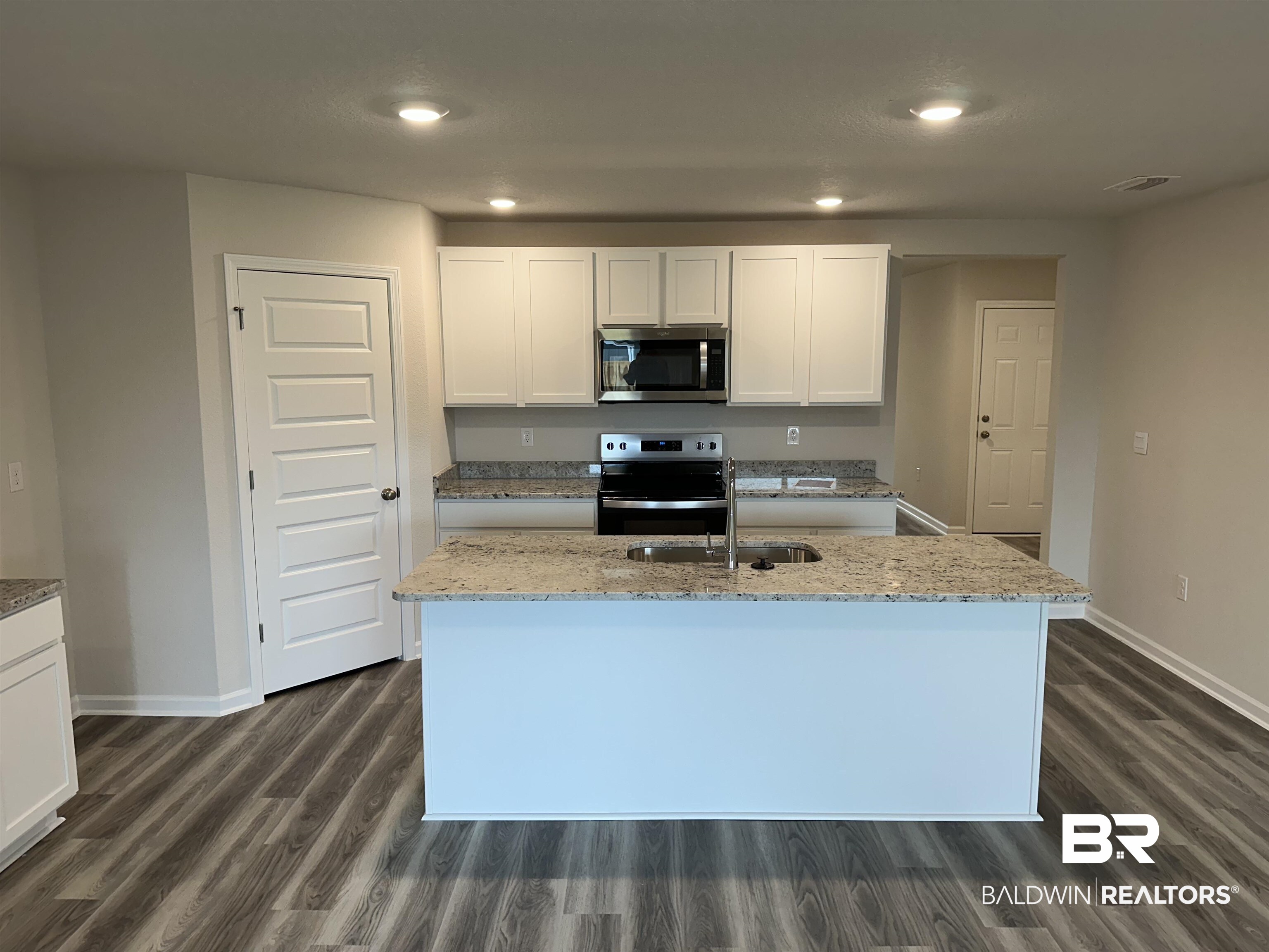 1238 Hayward Loop Foley, AL 36535 - Photo 23 of 46 Kitchen with a kitchen island with sink, dark wood-type flooring, white cabinets, sink, and appliances with stainless steel finishes
