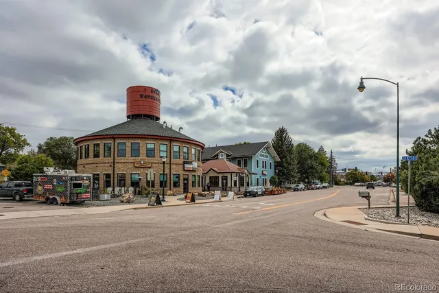 a front view of multi story residential apartment building with retail shops car parked and traffic signal