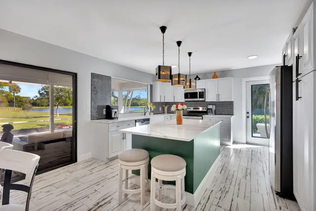 a kitchen with stainless steel appliances a dining table chairs and wooden floor