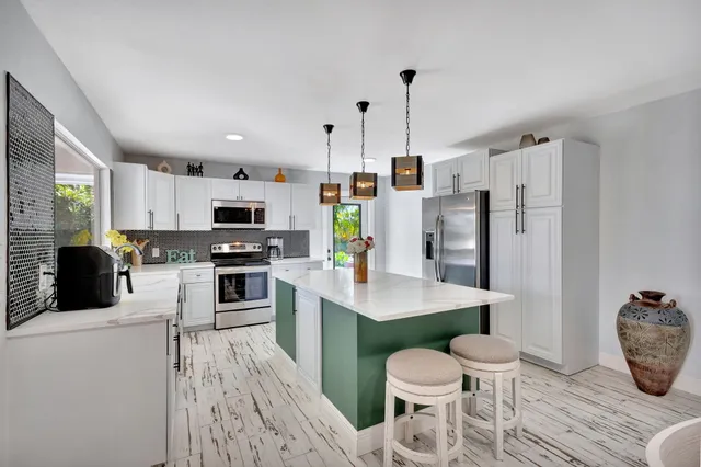 a kitchen with stainless steel appliances a refrigerator a stove a sink dishwasher and white cabinets with wooden floor