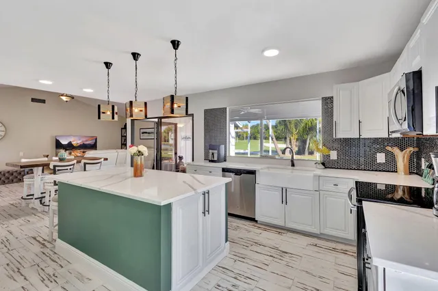 a kitchen with kitchen island granite countertop a sink appliances and cabinets