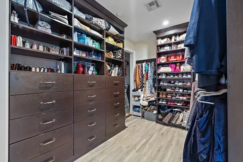 a view of walk in closet with clothes and shoes