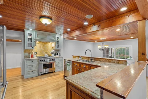 a large kitchen with stainless steel appliances granite countertop a sink and cabinets