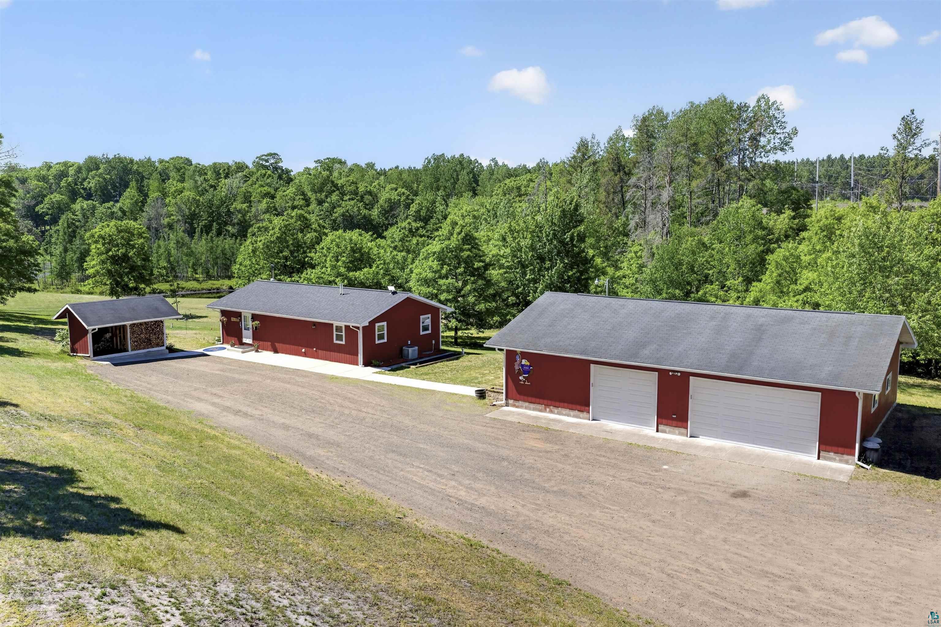 11702 East Mail Road Gordon, WI 54838 - Photo 1 of 60 Red-sided residence with an expansive gravel driveway, two-car detached garage, and an additional shed