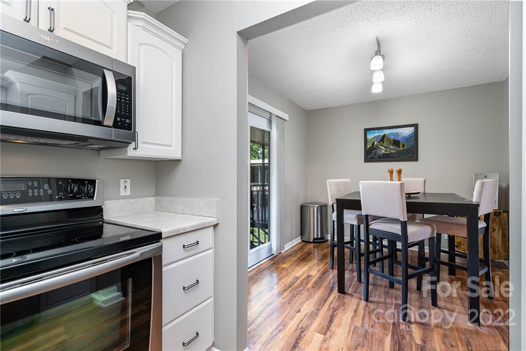 2612 Park Road, Unit D Charlotte, NC 28209 - Photo 7 of 23 a open kitchen with stainless steel appliances granite countertop a stove top oven a dining table and chairs with wooden floor