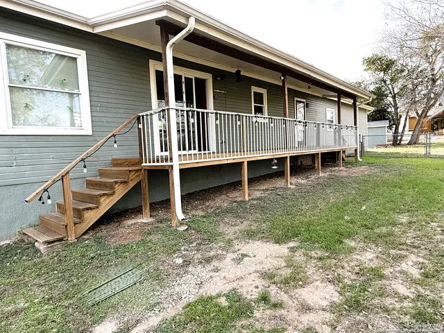 a backyard of a house with wooden deck stairs and furniture