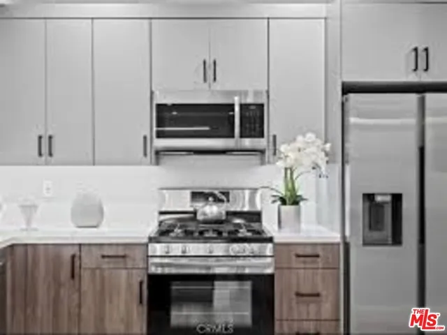 a kitchen with stainless steel appliances granite countertop white cabinets and a stove top oven