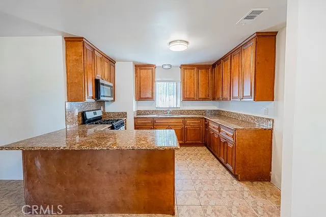 a kitchen with stainless steel appliances granite countertop wooden cabinets a stove top oven a sink and dishwasher