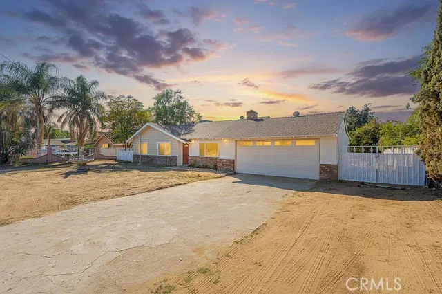 a view of yellow house with a yard and wooden fence