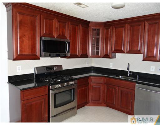 241 Prestwick Way Edison, NJ 08820 - Photo 3 of 9 a kitchen with granite countertop stainless steel appliances a sink a stove a microwave and wooden cabinets
