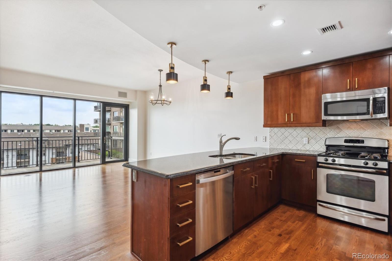 2990 East 17th Avenue, Unit 803 Denver, CO 80206 - Photo 2 of 29 a kitchen with stainless steel appliances granite countertop a stove a sink and a microwave