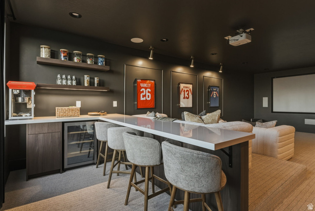 923 North Emery Lane Elk Ridge, UT 84651 - Photo 76 of 101 Dedicated entertainment room featuring a built-in bar with a beverage refrigerator, layered floating shelves with integrated lighting, and a large projection screen