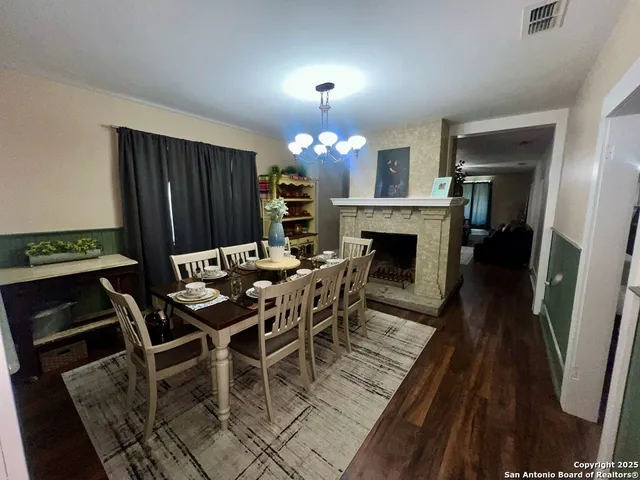 a view of a dining room with furniture wooden floor fireplace and a chandelier
