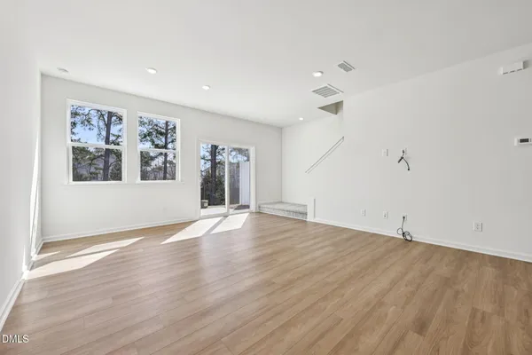 an empty room with wooden floor and a ceiling fan