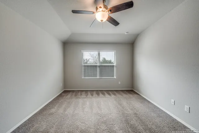 an empty room with a window and a fan