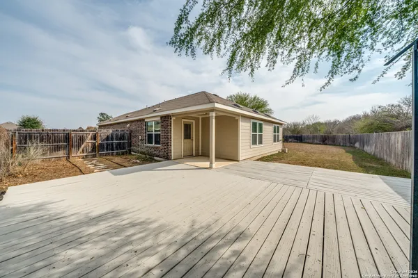 a front view of house with yard slide and large trees with wooden fence