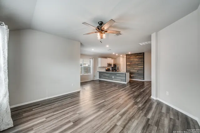 a view of a room with wooden floor and a ceiling fan