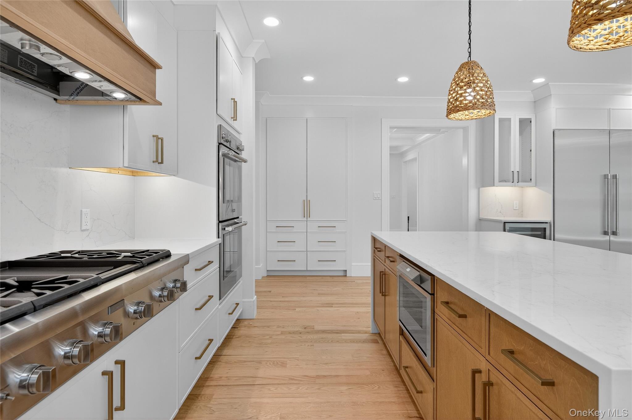 654 Caledonia Road Dix Hills, NY 11746 - Photo 15 of 42 Kitchen with light stone countertops, appliances with stainless steel finishes, light wood-style floors, tasteful backsplash, and brown cabinets