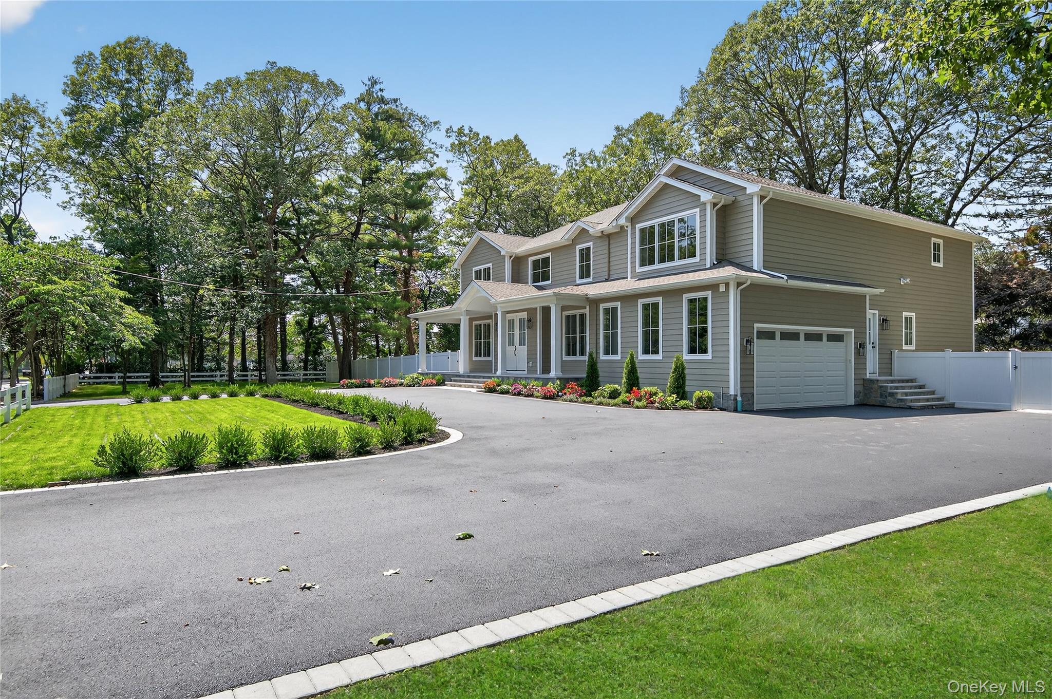 654 Caledonia Road Dix Hills, NY 11746 - Photo 4 of 42 View of front of house with a porch, an attached garage, driveway, and view of wooded area