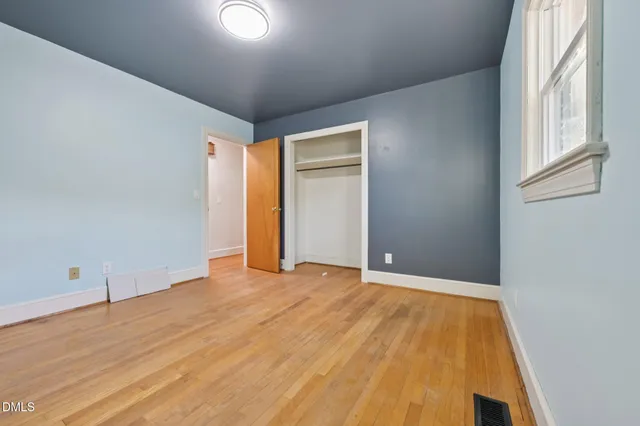a view of an empty room with wooden floor and a window