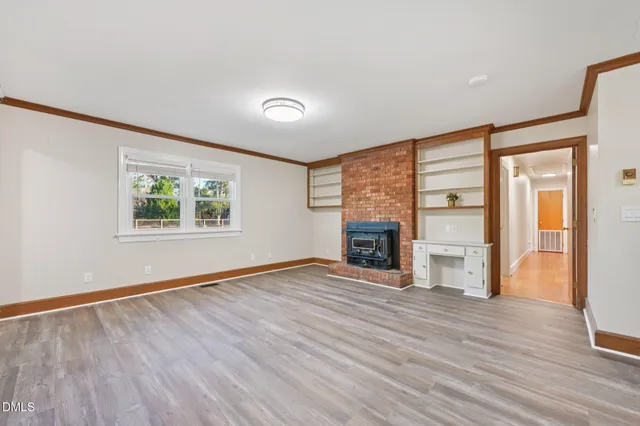 an empty room with windows fireplace and wooden floor
