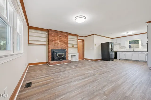 a view of empty room with wooden floor and fireplace