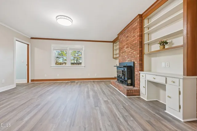 a view of empty room with wooden floor and fireplace