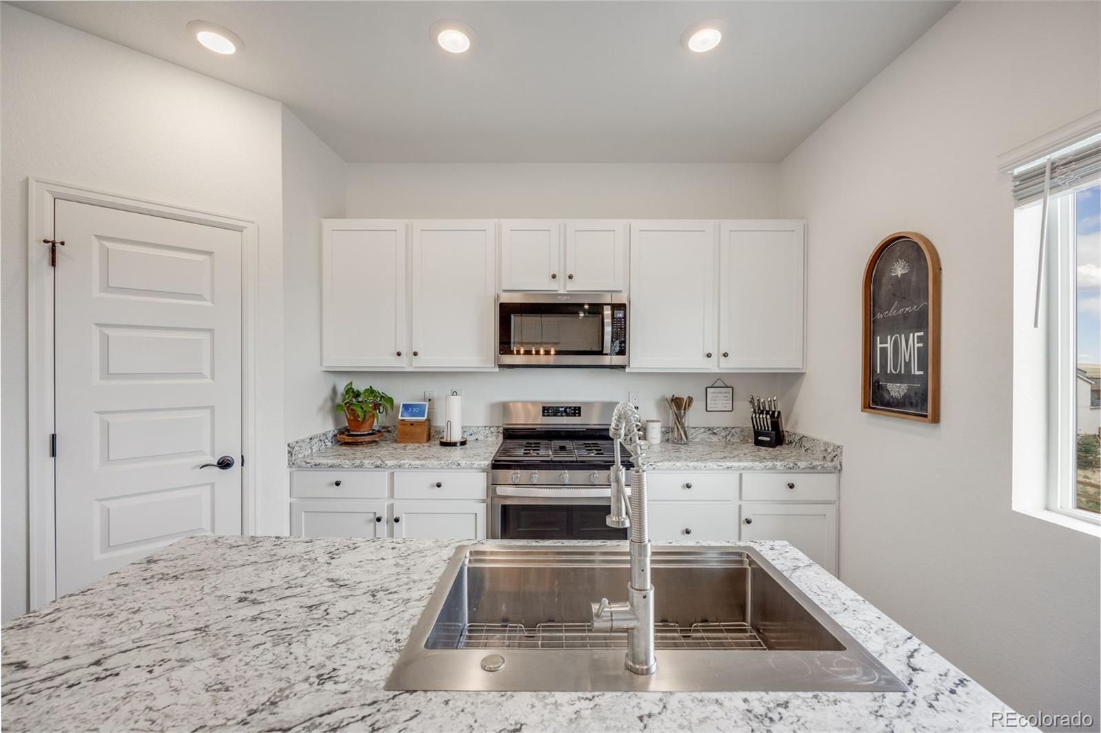 4811 River Highlands Loop Elizabeth, CO 80107 - Photo 12 of 37 a kitchen with granite countertop a stove a sink and a microwave