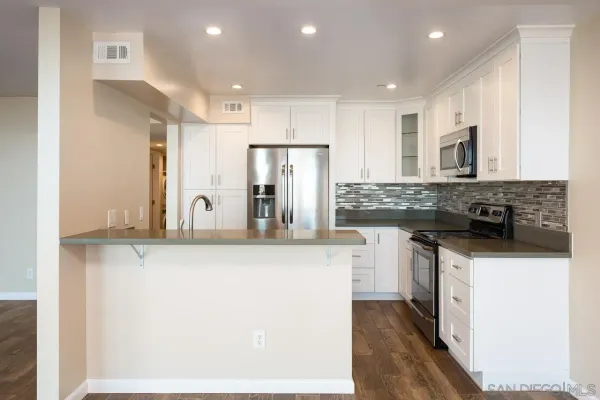 a kitchen with stainless steel appliances granite countertop a refrigerator a stove and a sink with wooden floor