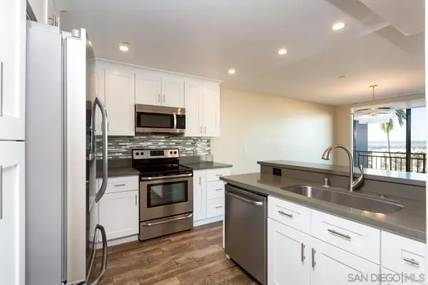 a kitchen with granite countertop a sink stainless steel appliances and cabinets