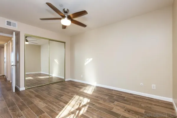 an empty room with wooden floor and fan