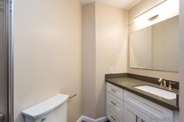 a bathroom with a granite countertop sink and a toilet