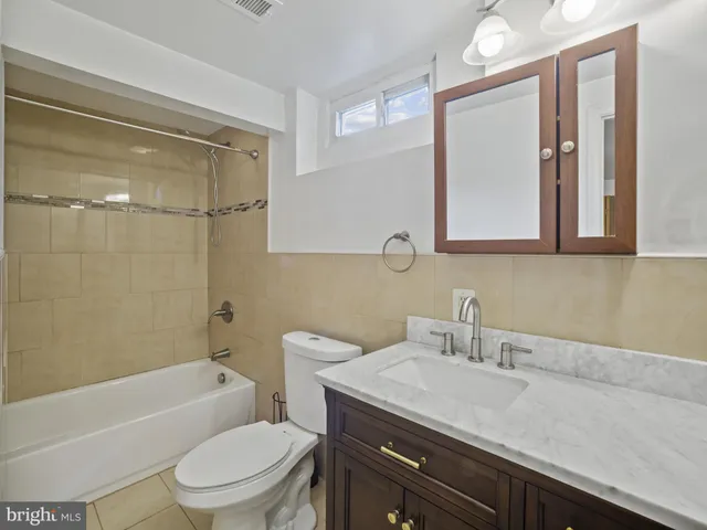 a bathroom with a granite countertop sink a toilet a mirror and bathtub