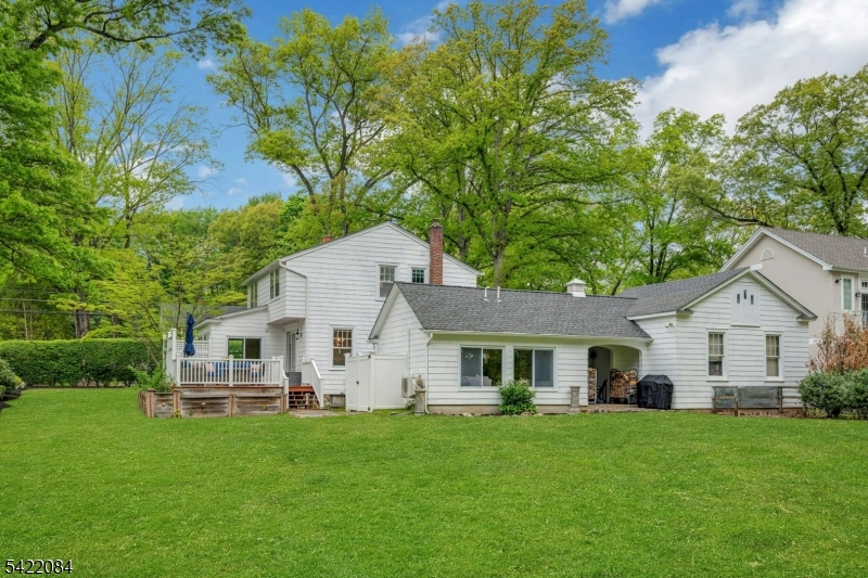122 Kenilworth Road Mountain Lakes, NJ 07046 - Photo 5 of 45 a view of a white house in front of a big yard with large trees and plants