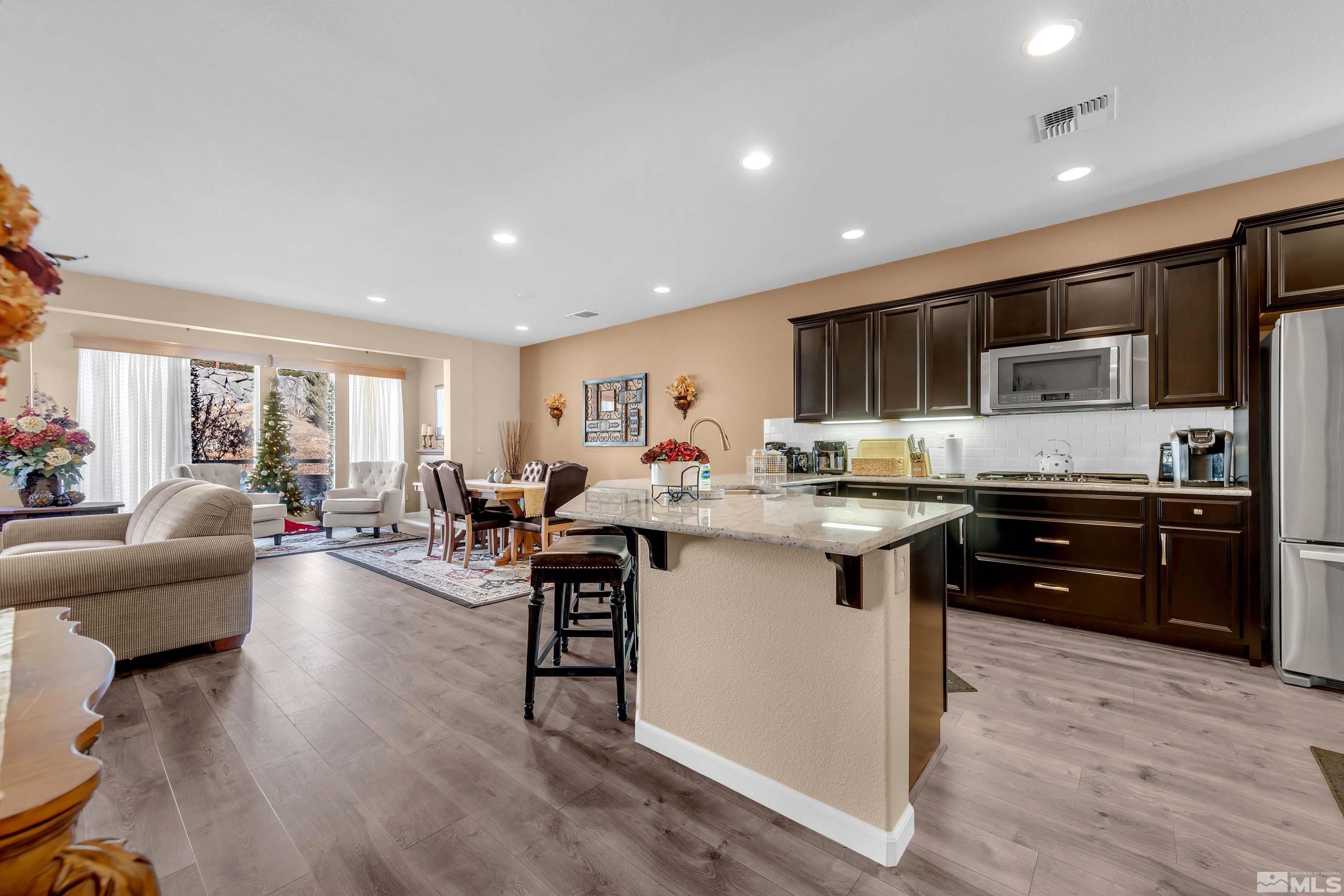 895 Larrimore Trail Reno, NV 89523 - Photo 8 of 39 a kitchen with stainless steel appliances kitchen island granite countertop a refrigerator a sink dishwasher a stove and a dining table with wooden floor