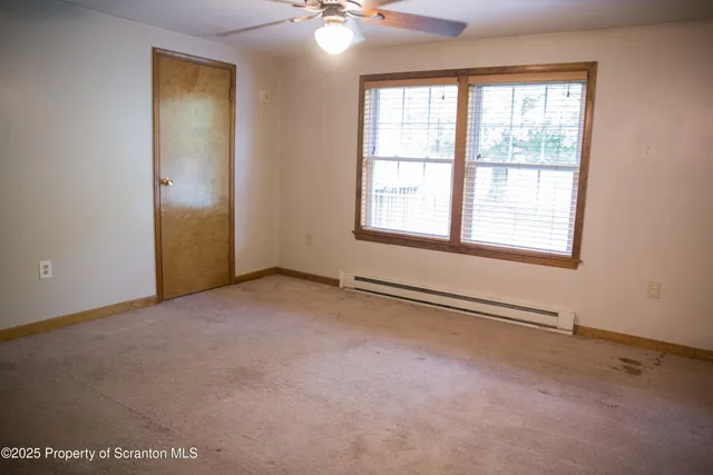 an empty room with chandelier fan and windows
