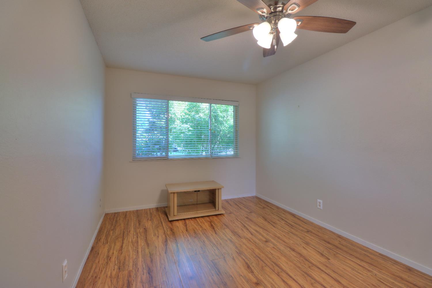 6265 North Colonial Avenue Fresno, CA 93704 - Photo 11 of 22 an empty room with wooden floor chandelier fan and windows