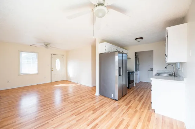 a view of a kitchen with a sink a refrigerator and wooden floor