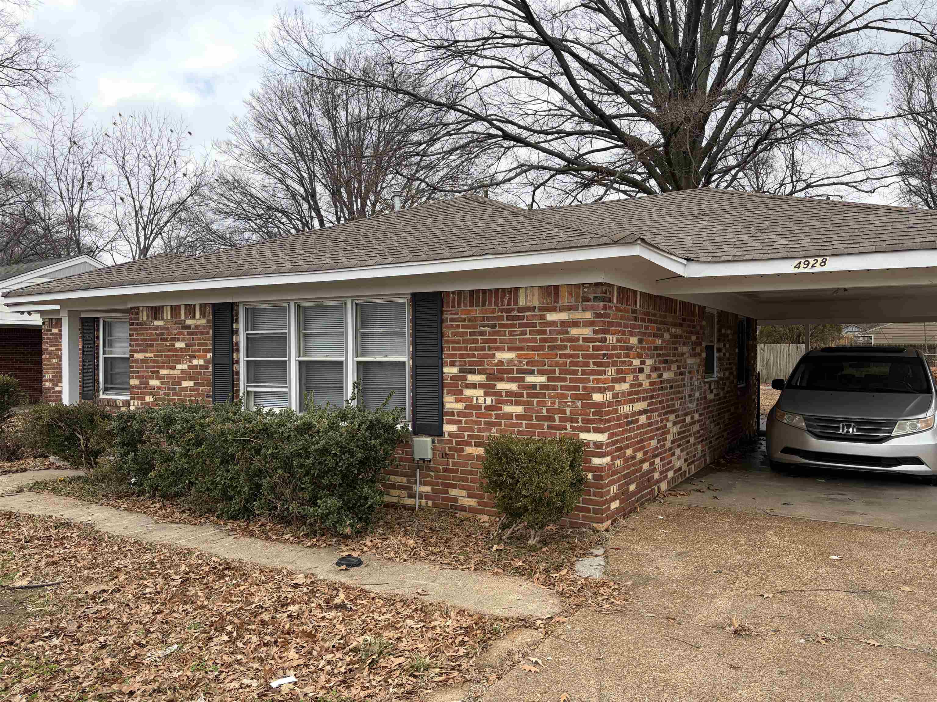 4928 Willow Road Memphis, TN 38117 - Photo 2 of 16 View of side of home with brick siding, concrete driveway, a carport, and a shingled roof