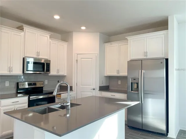 a kitchen with stainless steel appliances granite countertop a sink a stove and a refrigerator