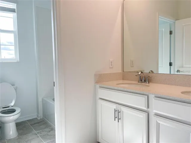 a bathroom with a granite countertop sink a toilet and a mirror