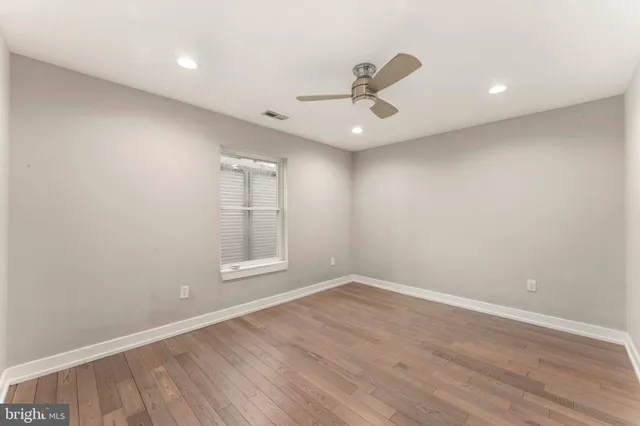 an empty room with wooden floor fan and windows