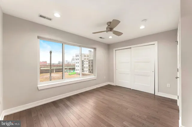 a view of an empty room with a window and wooden floor