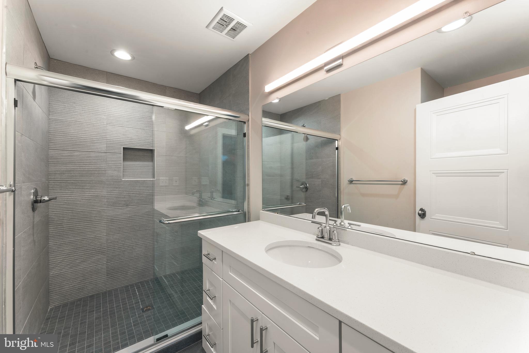 1407 North 8th Street, Unit A1 Philadelphia, PA 19122 - Photo 19 of 22 a bathroom with a shower sink vanity and mirror