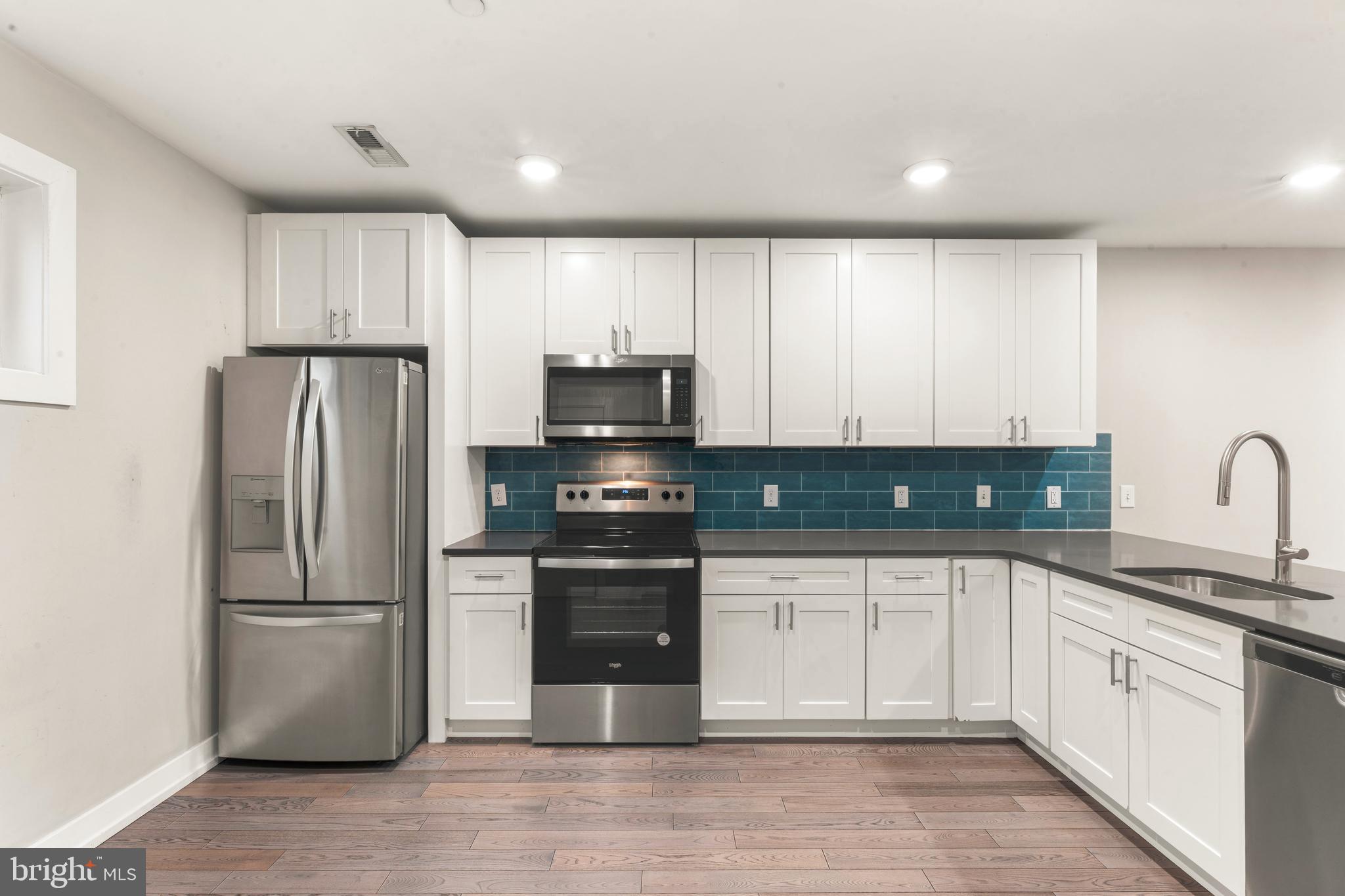 1407 North 8th Street, Unit A1 Philadelphia, PA 19122 - Photo 6 of 22 a kitchen with white cabinets stainless steel appliances and a sink