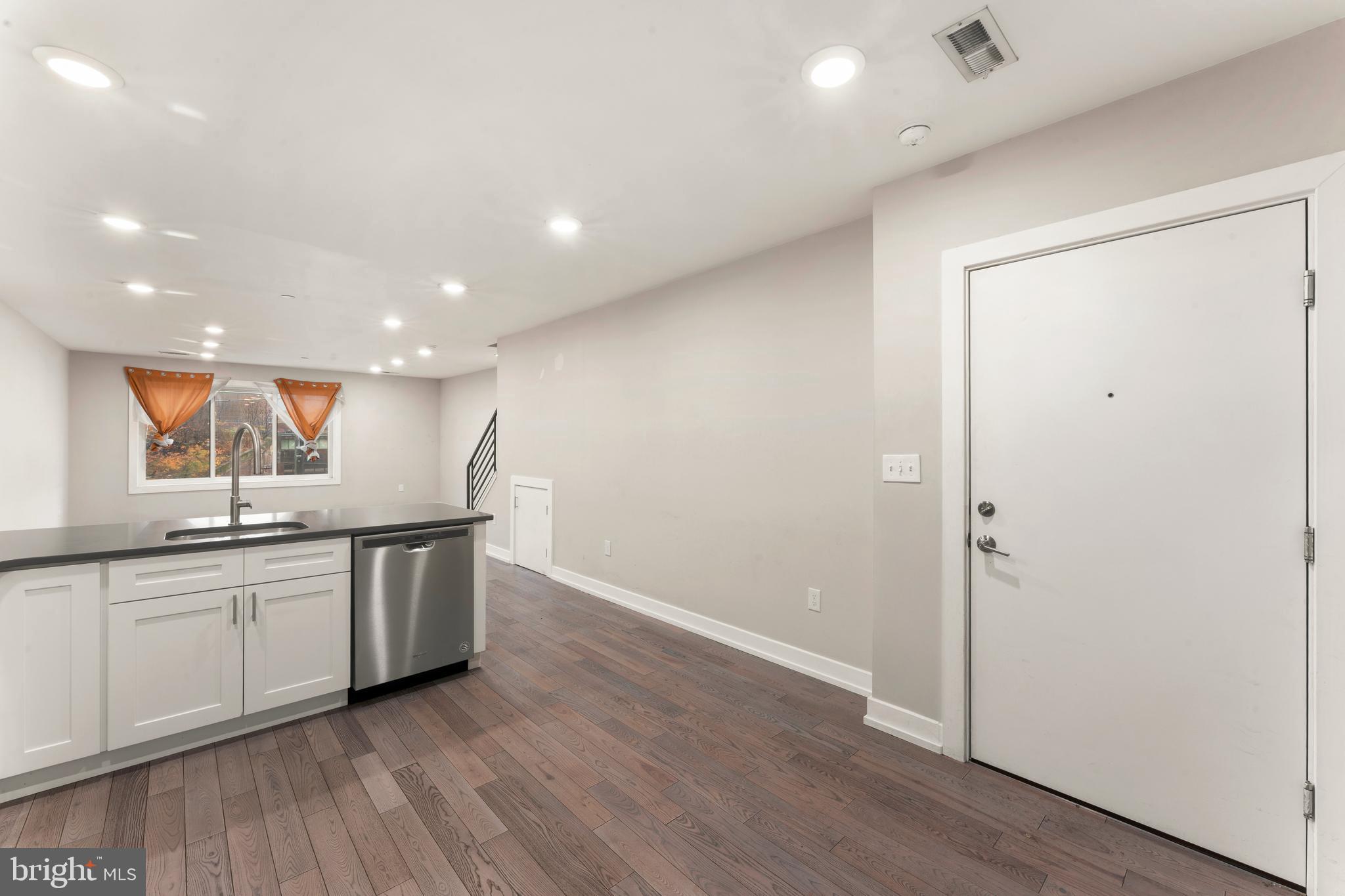 1407 North 8th Street, Unit A1 Philadelphia, PA 19122 - Photo 7 of 22 a open kitchen with stainless steel appliances granite countertop a sink and cabinets with wooden floor